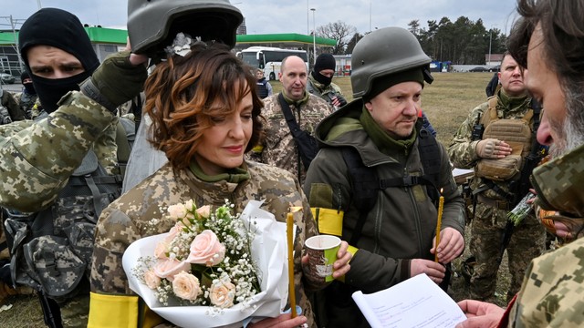 Prajurit pertahanan wilayah Ukraina, Valery dan Lesya, menikah tidak jauh dari check-point di pinggiran Kiev, Ukraina, pada 6 Maret 2022.
 Foto: Genya Savilov/AFP