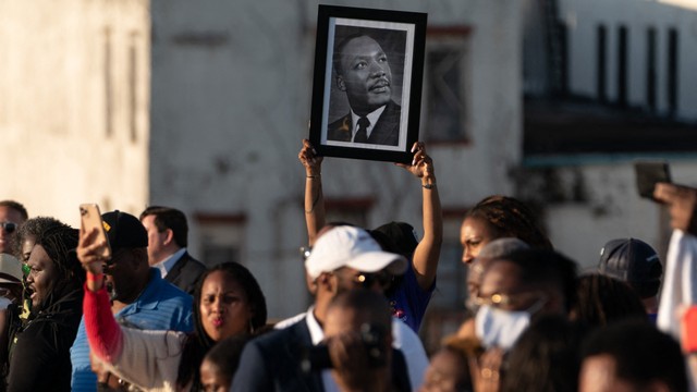 Seorang wanita memegang foto mendiang Pendeta Martin Luther King Jr. saat berbaris melintasi Jembatan Edmund Pettus dalam rangka memperingati "Minggu Berdarah" di Jembatan Edmund Pettus di Selma, Alabama, Amerika Serikat (6/2). Foto: Elijah Nouvelage/AFP