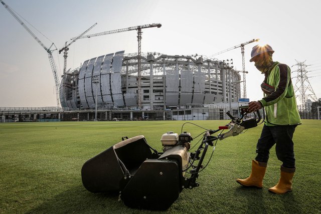 Pekerja memotong rumput lapangan latihan di kawasan Jakarta International Stadium (JIS), Tanjung Priok, Jakarta, Selasa (12/10/2021). Foto: Dhemas Reviyanto/Antara Foto