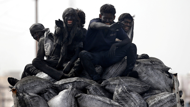 Pekerja batu bara melakukan perjalanan di belakang truk mereka di Barsana, India. Foto: REUTERS/Amit Dave