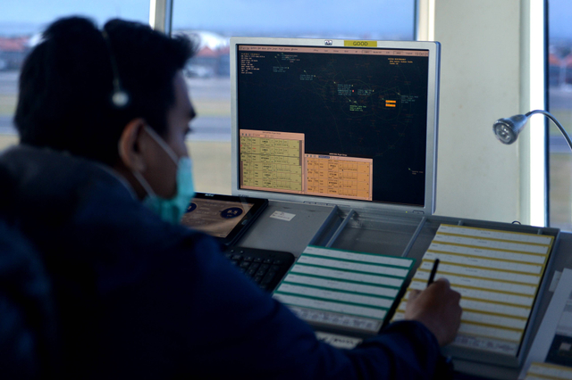 Petugas memantau dan mengatur pergerakan pesawat udara di menara Air Traffic Controller (ATC) Bandara Internasional I Gusti Ngurah Rai, Bali, Rabu (13/10/2021). Foto: Fikri Yusuf/Antara Foto