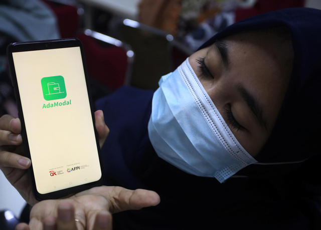 Pekerja menunjukan aplikasi pinjaman online "AdaModal" usai penggerebekan kantor jasa pinjaman online oleh Dit Reskrimsus Polda Metro Jaya, Kamis (14/10/2021). Foto: Muhammad Iqbal/Antara Foto