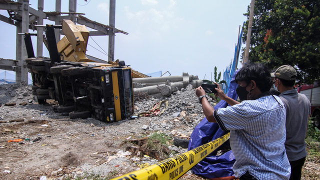 Warga memotret alat berat crane yang jatuh menimpa rumah warga di Pancoran Mas, Depok, Jawa Barat, Jumat (15/10/2021). Foto: Asprilla Dwi Adha/ANTARA FOTO