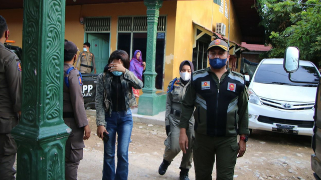 ANGGOTA Satuan Polisi Pamong Praja (Satpol PP) membawa seorang perempuan yang bekerja berkedok pijat kesehatan namun pijat plus-plus. 