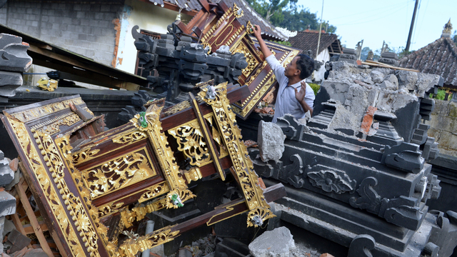 Warga mengamati puing-puing bangunan tempat ibadah yang rusak akibat gempa di kawasan Besakih, Karangasem, Bali, Sabtu (16/10/2021). Foto: Fikri Yusuf/ANTARA FOTO