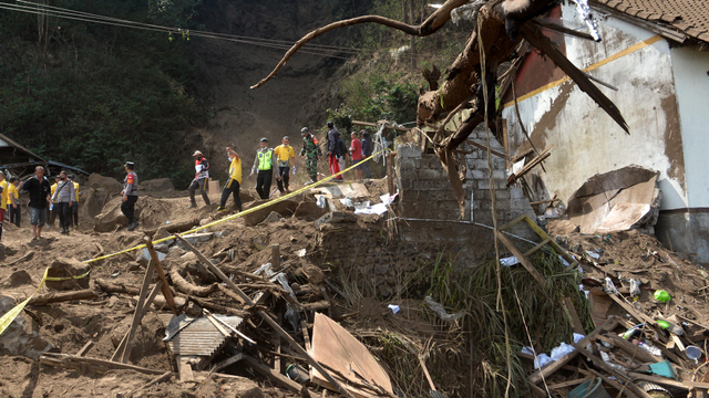 Petugas dan warga berjalan di dekat rumah yang rusak tertimbun longsoran bukit akibat gempa di kawasan Trunyan, Kintamani, Bangli, Bali, Sabtu (16/10/2021). Foto: Fikri Yusuf/Antara Foto