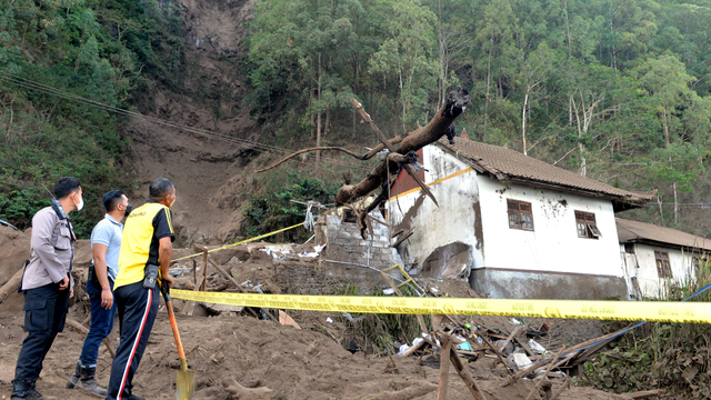 Petugas mengamati rumah yang rusak tertimbun longsoran bukit akibat gempa di kawasan Trunyan, Kintamani, Bangli, Bali, Sabtu (16/10/2021). Foto: Fikri Yusuf/Antara Foto
