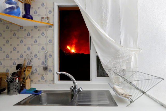 Lava terlihat melalui jendela sebuah rumah di El Paso setelah letusan gunung berapi di Pulau Canary La Palma, Spanyol. Foto: Juan Medina/Reuters