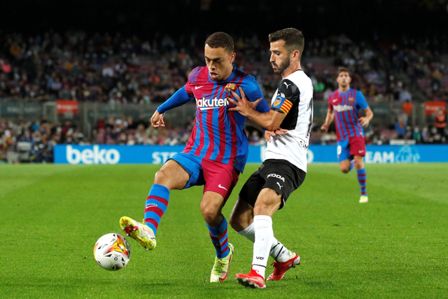 Pemain FC Barcelona Sergino Dest berusaha melewati pemain Valencia Jose Gaya pada pertandingan lanjutan Liga Spanyol di Camp Nou, Barcelona, Spanyol. Foto: Albert Gea/REUTERS