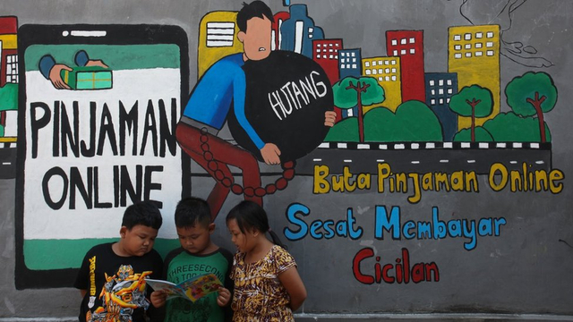 Sejumlah anak membaca bersama di dekat dinding bermural di kawasan Tempurejo, Surabaya, Jawa Timur, Selasa (7/9/2021). Mural tersebut sebagai sarana imbauan kepada masyarakat terhadap bahaya pinjaman daring atau 'online' (pinjol) ilegal yang sekarang lagi marak