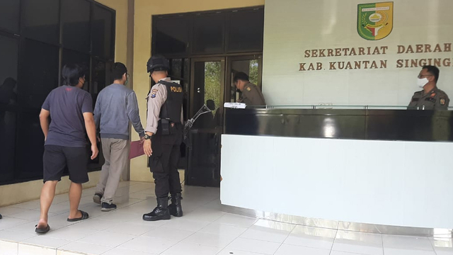 PENYIDIK KPK dikawal polisi bersenjata laras panjang memasuki kantor Bupati Kuansing, Riau, untuk menggeledah ruangan Bupati Andi Putra, Selasa (19/10/2021). 