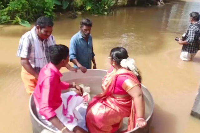 Pasangan India didorong melewati air banjir di panci masak untuk pernikahan mereka. Foto: AFP