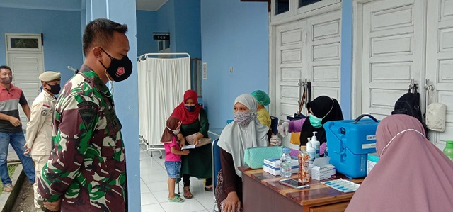 anggota TNI memantau proses vaksinasi terhadap warga