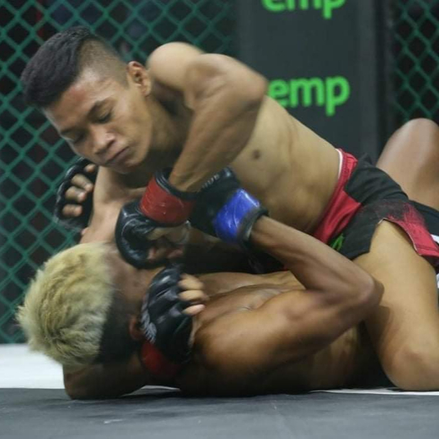 Aminudin mendaratkan bogem ke arah wajah lawannya dalam pertandingan MMA. Foto: IST/InfoPBUN