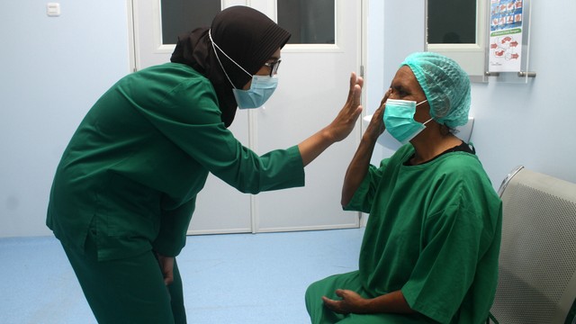 Seorang tenaga kesehatan berbincang dengan warga yang akan menjalani operasi katarak saat bakti sosial (baksos). Foto: ANTARA FOTO/Jessica Helena Wuysang