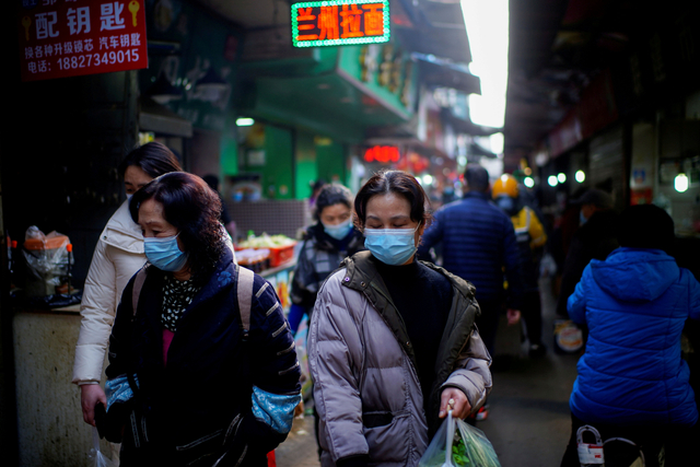Orang-orang yang mengenakan masker berjalan di pasar jalanan pada bulan-bulan awal wabah penyakit coronavirus (COVID-19) di Wuhan Foto: Reuters