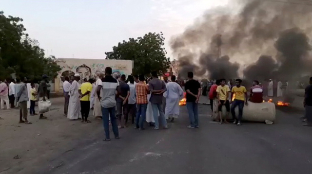 Orang-orang dekat benda-benda terbakar yang tergeletak di jalan-jalan Kartoum, Sudan, di tengah laporan kudeta, 25 Oktober 2021. Foto: RASD SUDAN NETWORK melalui REUTERS