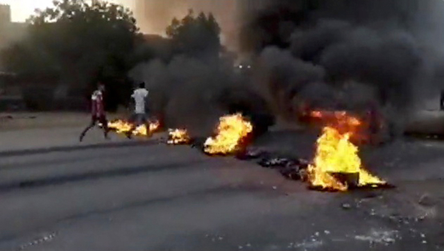 Orang-orang berjalan melewati benda-benda terbakar yang tergeletak di jalan-jalan Kartoum, Sudan, di tengah laporan kudeta, 25 Oktober 2021. Foto: RASD SUDAN NETWORK melalui REUTERS