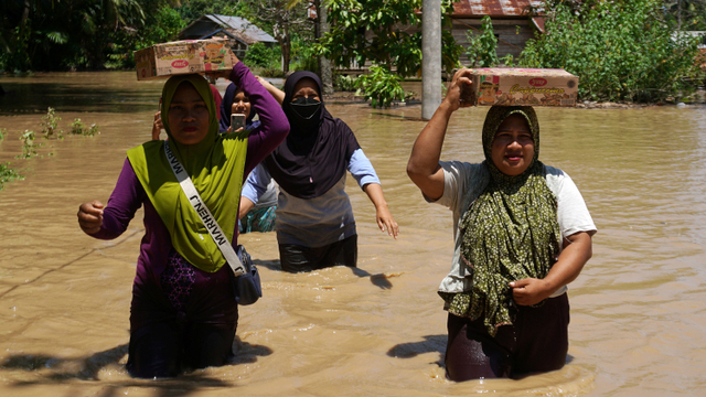 Warga korban banjir membawa bantuan logistik di desa Kabuloang, Kecamatan Kalukku, Mamuju, Sulawesi Barat, Senin (25/10).  Foto: Akbar Tado/ANTARA FOTO