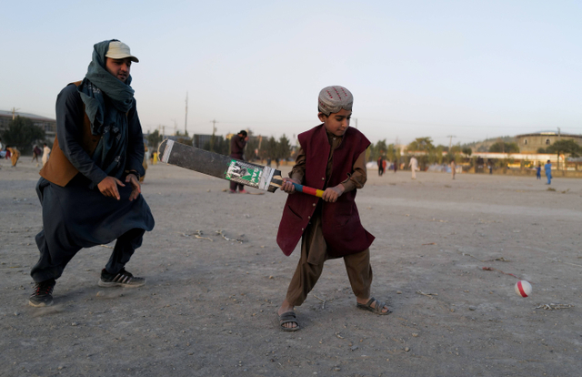 Khobiab (7) sedang belajar bermain kriket berpose di sebuah taman bermain di Kabul, Afghanistan. Foto: Zohra Bensemra/Reuters