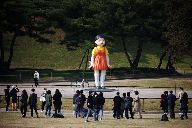 Warga melihat boneka raksasa dalam serial Squid Game yang dipamerkan di sebuah taman di Seoul, Korea Selatan. Foto: Kim Hong- Jihee/REUTERS
