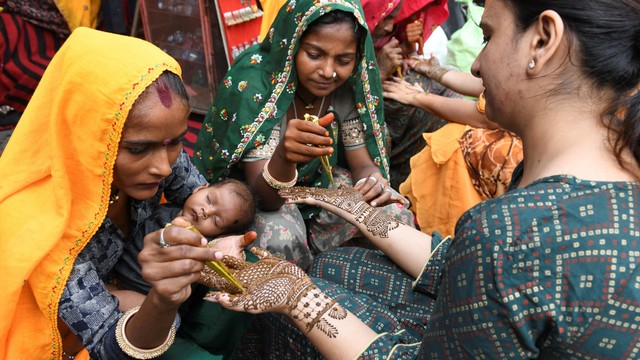 Para perempuan di Amritsar, India menghias tangan mereka dengan pacar kuku atau Henna di malam festival Chauth.  Foto: NARINDER NANU / AFP