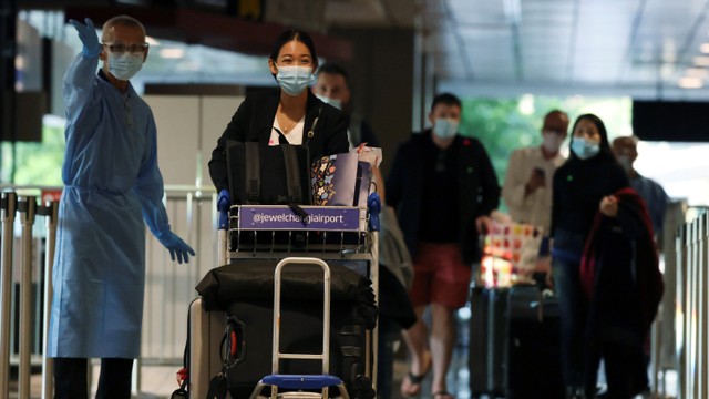 Penumpang menggunakan masker saat tiba di Bandara  di Singapura. Foto: Edgar Su/REUTERS