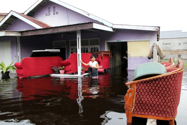 Seorang warga memindahkan barang-barangnya untuk menghindar dari banjir di Kelurahan Bumi Ayu Dumai, Riau, Kamis (28/10/2021). Foto: Aswaddy Hamid/Antara Foto