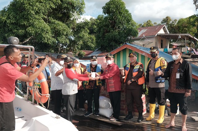 Ria Norsan menyerahkan bantuan untuk warga terdampak banjir di Desa Tanjung, Kecamatan Sekadau Hilir. Foto: Dok. Prokopim