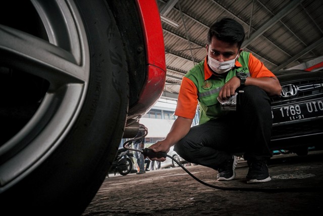 Petugas Dinas Lingkungan Hidup DKI Jakarta menguji emisi kendaraan bermotor di bengkel Dinas Lingkungan Hidup Foto: Jamal Ramadhan/kumparan