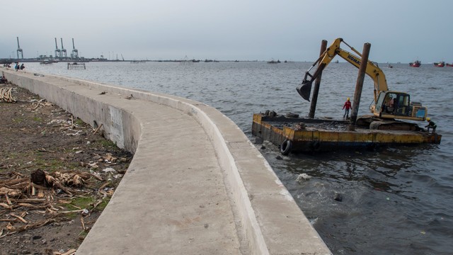 Pekerja menggunakan ekskavator untuk menyelesaikan pembangunan tanggul laut di Cilincing, Jakarta, Kamis (4/11/2021). Foto: ANTARA FOTO/Aditya Pradana Putra