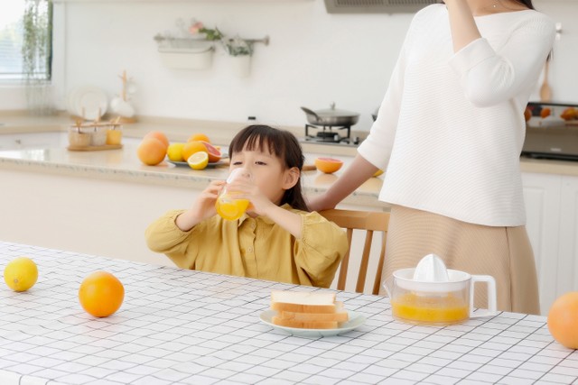 Anak makan atau minum jeruk peras dengan kandungan vitamin C. Foto: Shutter Stock
