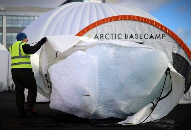 Seorang pekerja membuka kiriman bongkahan es dari Greenland setibanya di Konferensi Perubahan Iklim PBB (COP26) di Glasgow, Skotlandia, Inggris, Rabu (3/11). Foto: Hannah McKay/REUTERS
