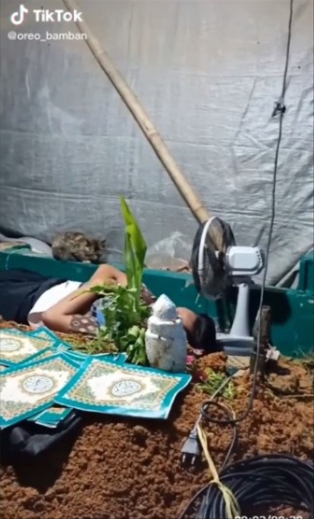 Heboh video pemuda menjaga hingga tidur di samping makam bak berada kos-kosan. (Foto: TIkTok/@oreo_bamban). 