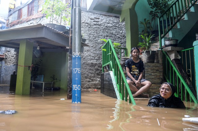 Dua orang warga berada di anak tangga ketika banjir merendam di kawasan Kebon Pala, Kampung Melayu, Jatinegara, Jakarta Timur, Senin (8/11/2021). Foto: M Risyal Hidayat/Antara Foto