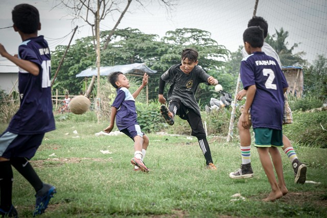 Sejumlah anak  bermain sepak bola di Desa Karangrahayu, Cikarang Utara, Jawa Barat. Foto: Iqbal Firdaus/kumparan