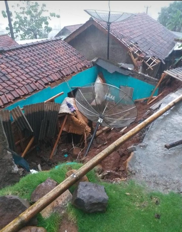 Tembok Penahan Tebing (TPT) setinggi 4 meter dengan panjang 10 meter di Dusun Sembir RT 04 RW 09 Desa Gunasari Kecamatan Sumedang Selatan, ambruk dan menimpa satu rumah, Minggu (14/11/2021). (Istimewa)