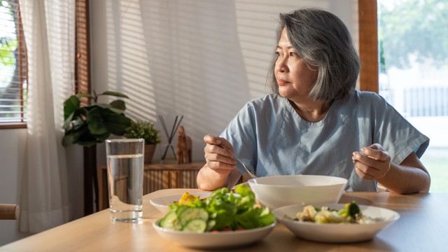 Ilustrasi perempuan lansia makan sendiri.