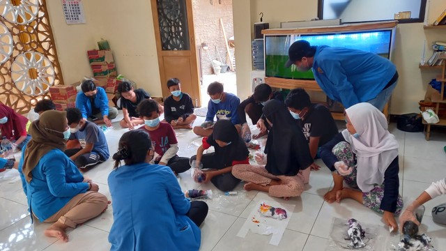 mahasiswa sedang mengamati kegiatan membuat kreativitas anak-anak karang taruna