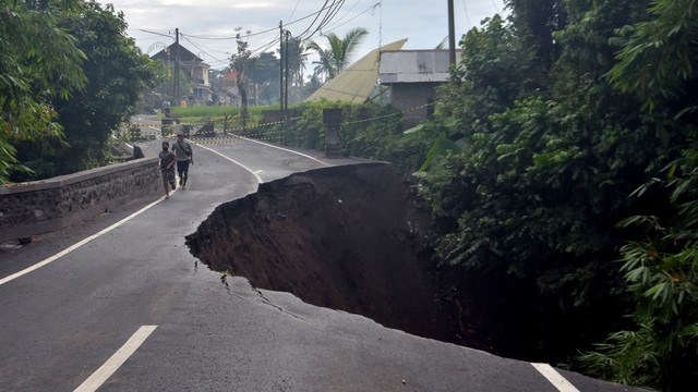 Warga melintas di dekat jalan ambles di Desa Pejeng, Gianyar, Bali, Selasa (16/11/2021). Foto: Nyoman Hendra Wibowo/ANTARA FOTO