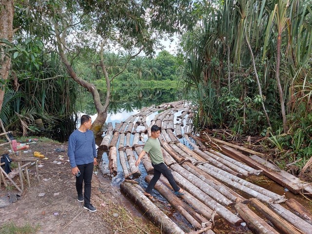 TUMPUKAN kayu yang dirangkai jadi rakit dialirkan melalui sungai untuk dijual dengan dikoordinir oleh Mat Ali alias Anak Jenderal. 