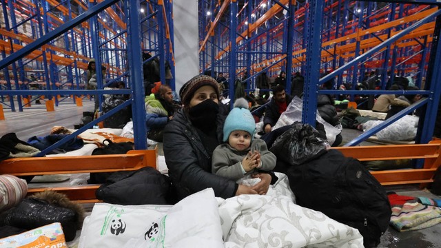 Para migran tinggal di pusat transportasi dan logistik dekat titik perbatasan Bruzgi di perbatasan Belarusia-Polandia di wilayah Grodno pada 16 November 2021. Foto: Guchek / BELTA / AFP