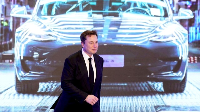 CEO Tesla Inc, Elon Musk berjalan di samping layar yang menunjukkan gambar mobil Tesla Model 3. Foto: REUTERS/Aly Song