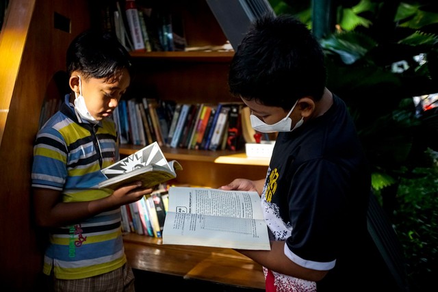 Dua orang anak membaca buku di perpustakaan mini Taman Suropat, Jakarta, Minggu (21/11).  Foto: Iqbal Firdaus/kumparan