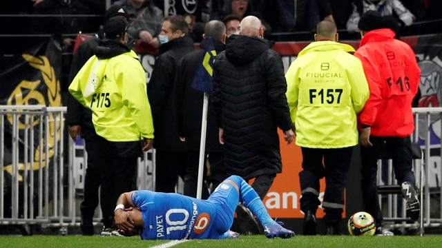 Pemain Olympique de Marseille Dimitri Payet jatuh setelah terkena botol air yang dilemparkan oleh seorang penggemar, di Stadion Groupama, Lyon, Prancis, Minggu (21/11). Foto: Benoit Tessier/REUTERS