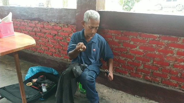 Said Agil Alatas (49) saat tengah meyemir sepatu pelanggannya. Foto: Rega/kepripedia.com
