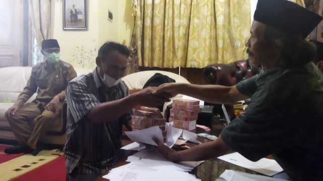 Pedagang tembakau Haji Rame (52) asal Desa Tlilir, Kecamatan Tlogomulyo, Kabupaten Temanggung, Jawa Tengah membayar tunai pembelian tembakau kepada petani, Senin (22/11/2021). Foto: ari/Tugu Jogja