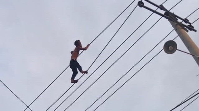 Seorang pria di Kabupaten Wajo, Sulawesi Selatan, bergelantungan di kabel listrik bertegangan tinggi. 