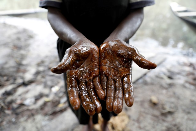 Seorang nelayan wanita menunjukkan tangannya yang ternoda minyak, menyusul tumpahan minyak di Santa Barbara, di Nembe, Bayelsa, Nigeria, Kamis (25/11). Foto: Temilade Adelaja/REUTERS