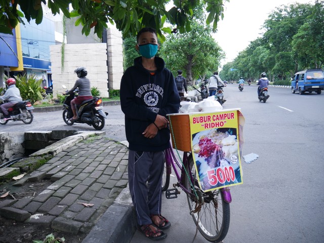 Adik Ridho (15) bocah kuat asal Surabaya yang kesehariannya berjualan bubur agar bisa terus sekolah dan membantu biaya berobat sakit tumor yang dideritanya. 